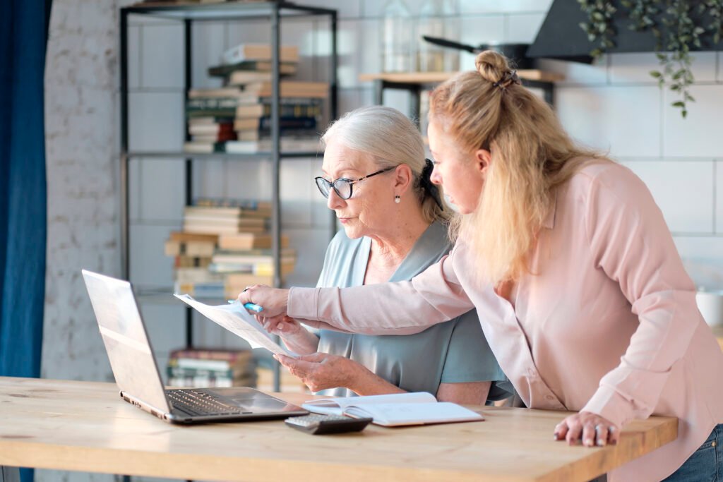 Zwei Frauen besprechen gemeinsam Dokumente am Laptop im Rahmen der Pflegeberatung in Herne